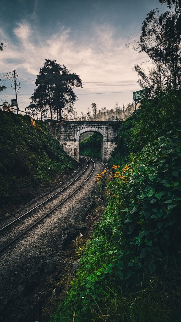 a train track going under a bridge on a cloudy day